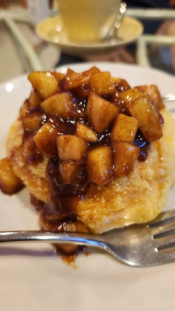 Close up of a soft, buttery pastry topped with sugar and caramelized apple with cinnamon