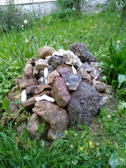 Ein Foto eines mittleren Steinhaufens auf grüner Wiese.
