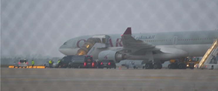 In der Morgendämmerung sieht man von der Seite einen Airbus 330, davor stehen einige Autos. Zwei Flugzeugtreppe sind beleuchtet und führen hoch zu den Eingangstüren des Flugzeugs.