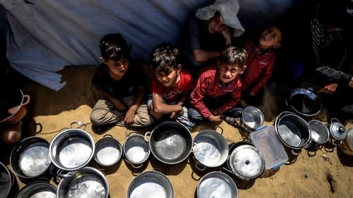Starving Palestinian children wait with empty containers in the hope of receiving food aid being blocked by Israel in Gaza.