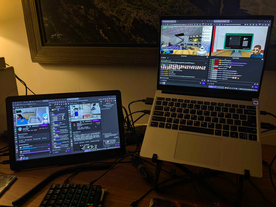A laptop is on a stand with an external monitor attached sitting to the left side. both screens show two twitch streams of streamers playing the game.