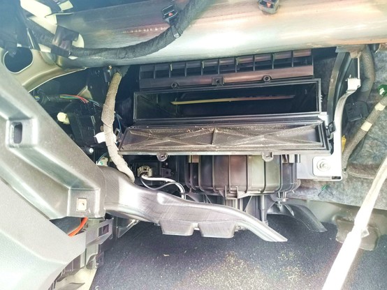 Inside of the passenger side footwell with the flap open and the cabin air filter removed to check for water.