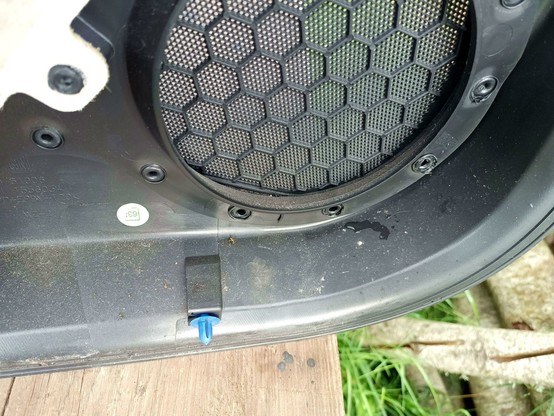 Close-up of a door panel that has been removed from the door. There's a small puddle of water under the speaker grille.