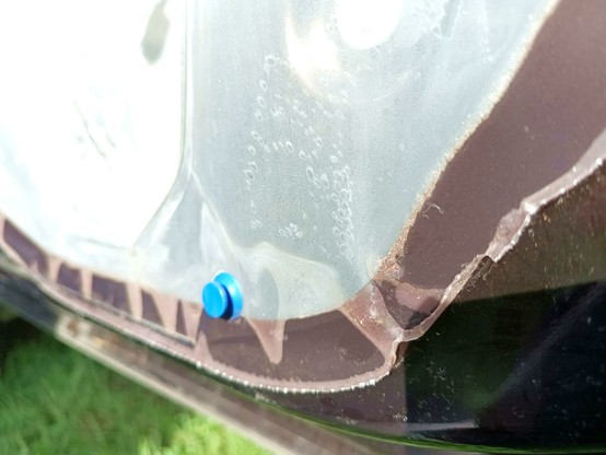 Close-up of one of the failed areas. Not all have detached completely, but this one goes all the way through and there are water droplets visible inside the semi-transparent plastic sheet. A blue plastic clip is stuck in the door and needs transferring to the panel.