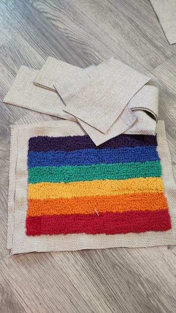 An upside down pride flag made with punch needle, along with cut parts of fabric that'll hopefully turn into a bag!