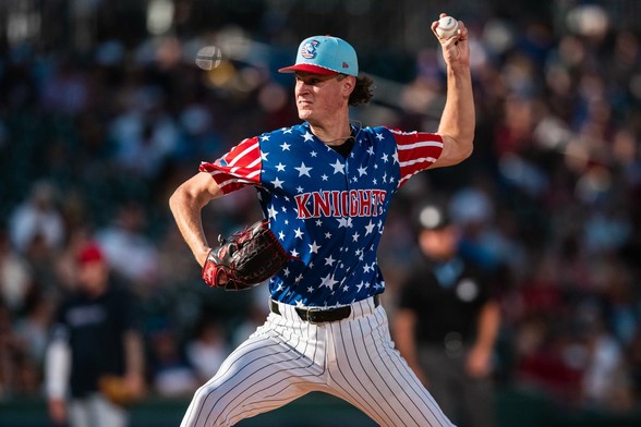 Noah Schultz winds up to throw a pitch while a red, white and blue uniform top with "Knights" across the chest.
