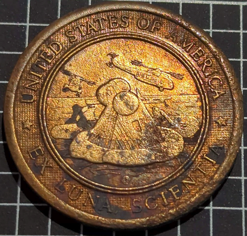 Landing module with helicopters around.  UNITED STATES OF AMERICA above and the mission motto "EX LUNA SCIENTIA" ("From the moon, knowledge") below