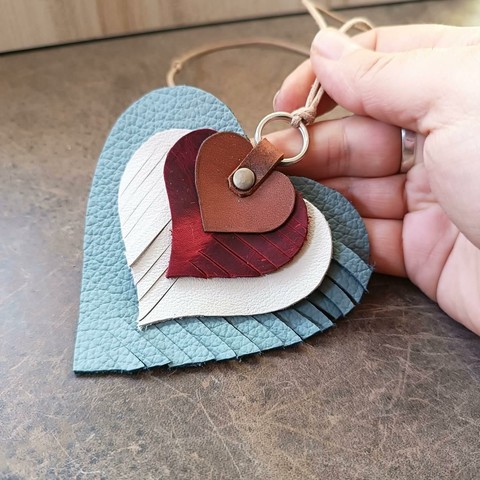 A leather charm I made. It can be used either as bag charm, or rearview mirror charm. It is layered leather hearts charm, with 4 heart shaped pieces, the bottom heart being the biggest one, the top one being the smallest one. It has a rotating vertical fringe design and the pieces are all different colors and leathers (and textures).