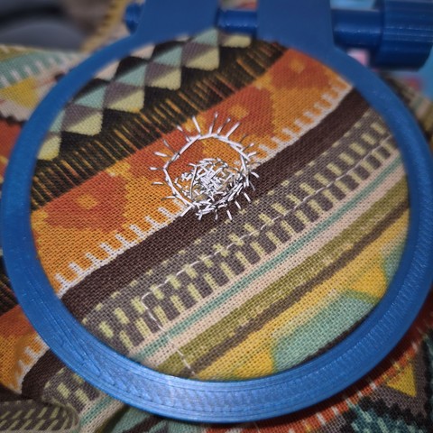 It looks kind of like a sun shape. A ring with rays coming out of it. The grey thread looks silverish and glowing.