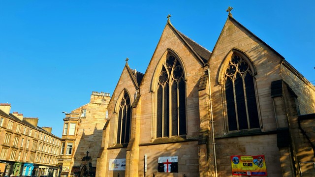 A blonde sandstone Victorian church and tenements in Glasgow.
