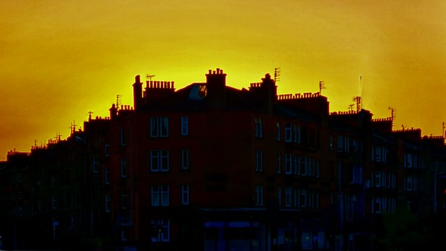 Glasgow tenements against a golden sunset.
