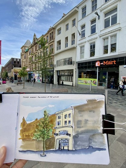 Some Houses in a street, one tall, thin and brighter than the others in the middle. In front of it is a sketchpad with a watercolor drawing of the scene, the thin building with some details, the others blurred.