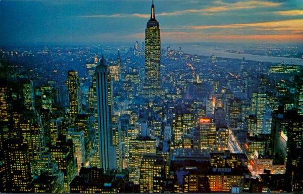 The view is over the city of New York. You see many skyscrapers with their lights on. In the dead center is the Empire State Building but Ford and just to the left is Rockefeller Center.