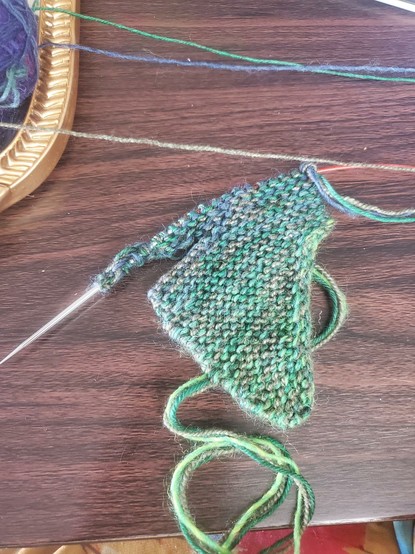 Small triangle of garter stitch knitting ona fake wood table