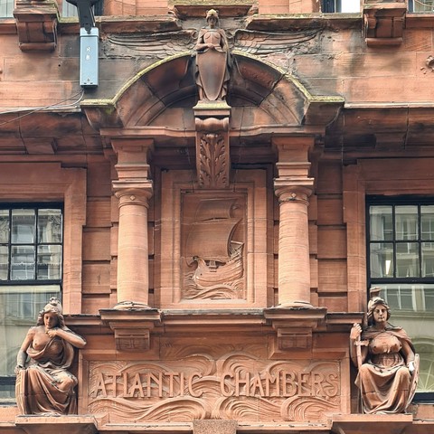 A large sculpted nameplate on a late Vicrorian commercial building.