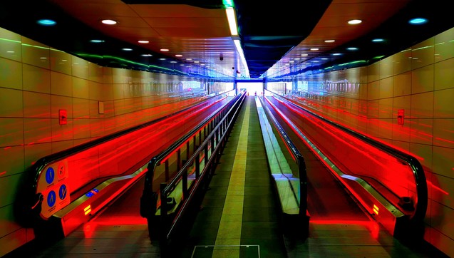 A pait of travellators lined with red neon lights.