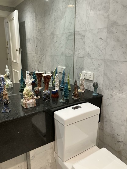 A series of small ceramic sculptures on a hotel bathroom sink
