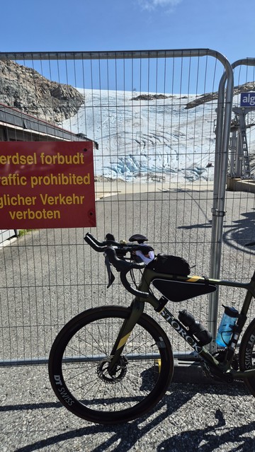 A green Gravelbike leans against a gate blocking the way to the Folgefonna Glacier edge.