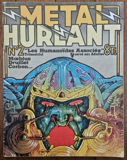 A cover of the Métal Hurlant magazine, produced by "Les Humanoïdes Associés", with cover art by Philippe Druillet, featuring a red-eyed monstrous character seemingly being tortured by some refined metallic mechanism.