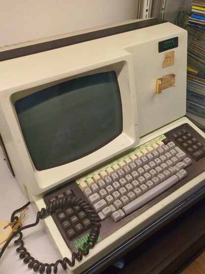 A screen embedded in a rectangular light beige case with a two-tone grey keyboard.