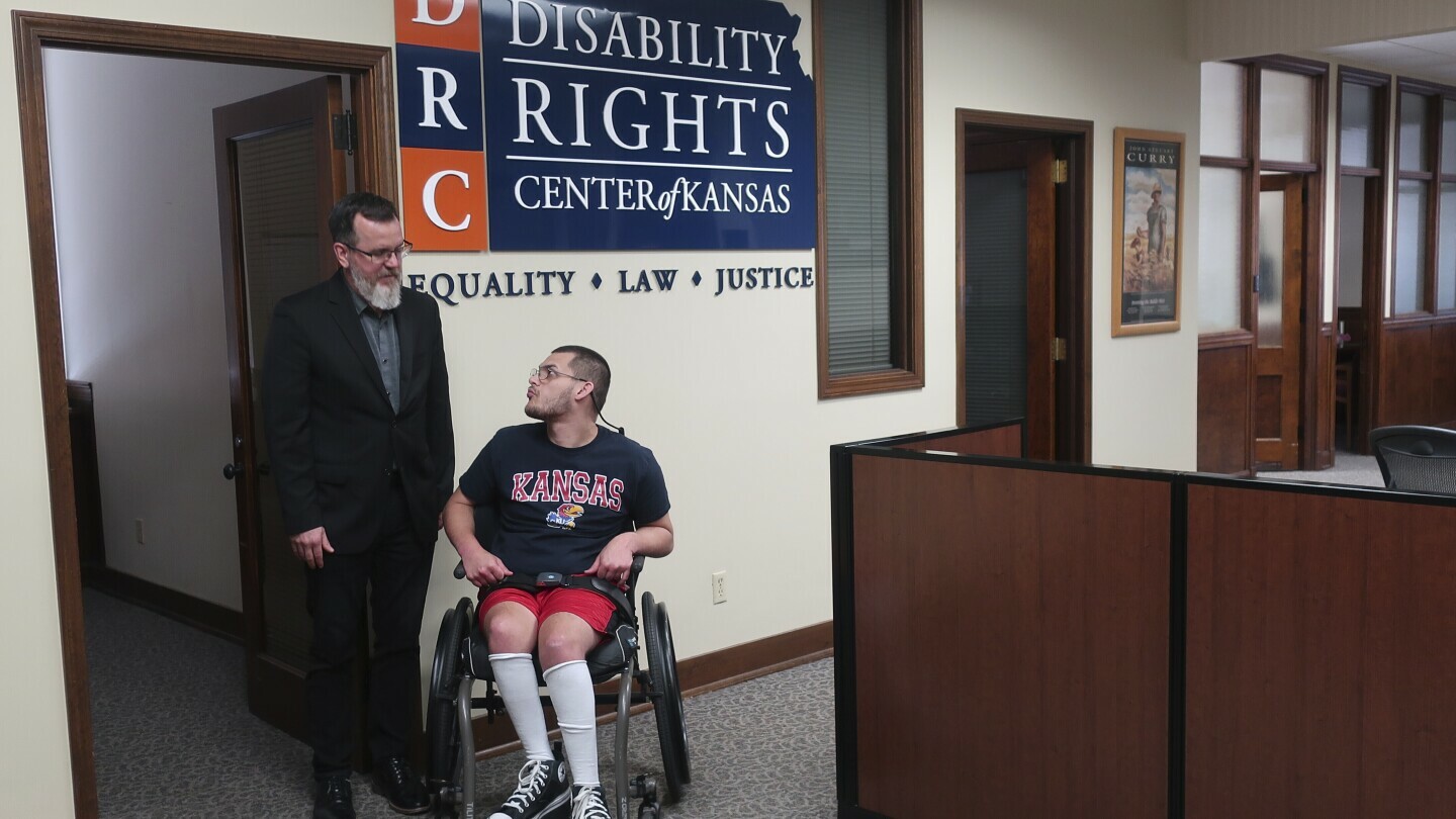 Rocky Nichols, left, executive director of the Disability Rights Center of Kansas, and Matthew Hull, right, a Kansas resident who has cerebral palsy, speak at the center in Topeka, Kans., June 18, 2025. (AP Photo/John Hanna)