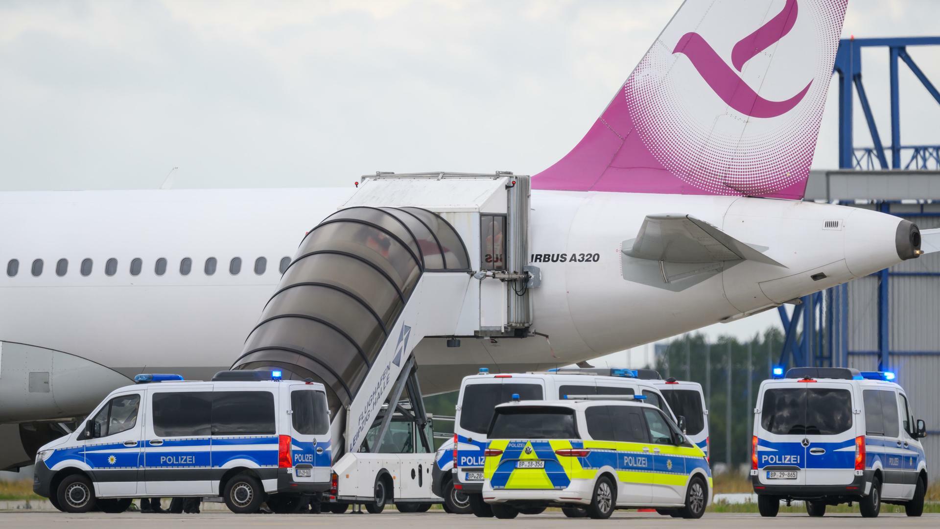 Polizeifahrzeug fahren auf dem Flughafen Leipzig/Halle an einem Airbus vor. 