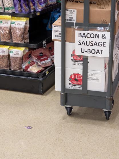 Grocery stocking cart labeled "bacon & sausage u-boat" for some reason