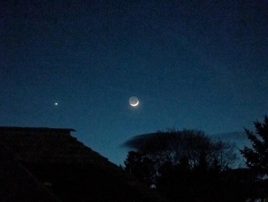 Very thin crescent moon but the entire disk is visible due to reflected light from earth illuminating it