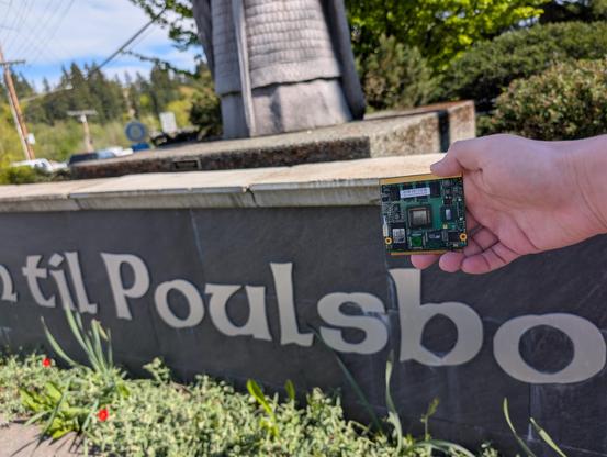 My hand holding a SoM with an Intel "Poulsbo" southbridge next to the "Poulsbo" text on the sign