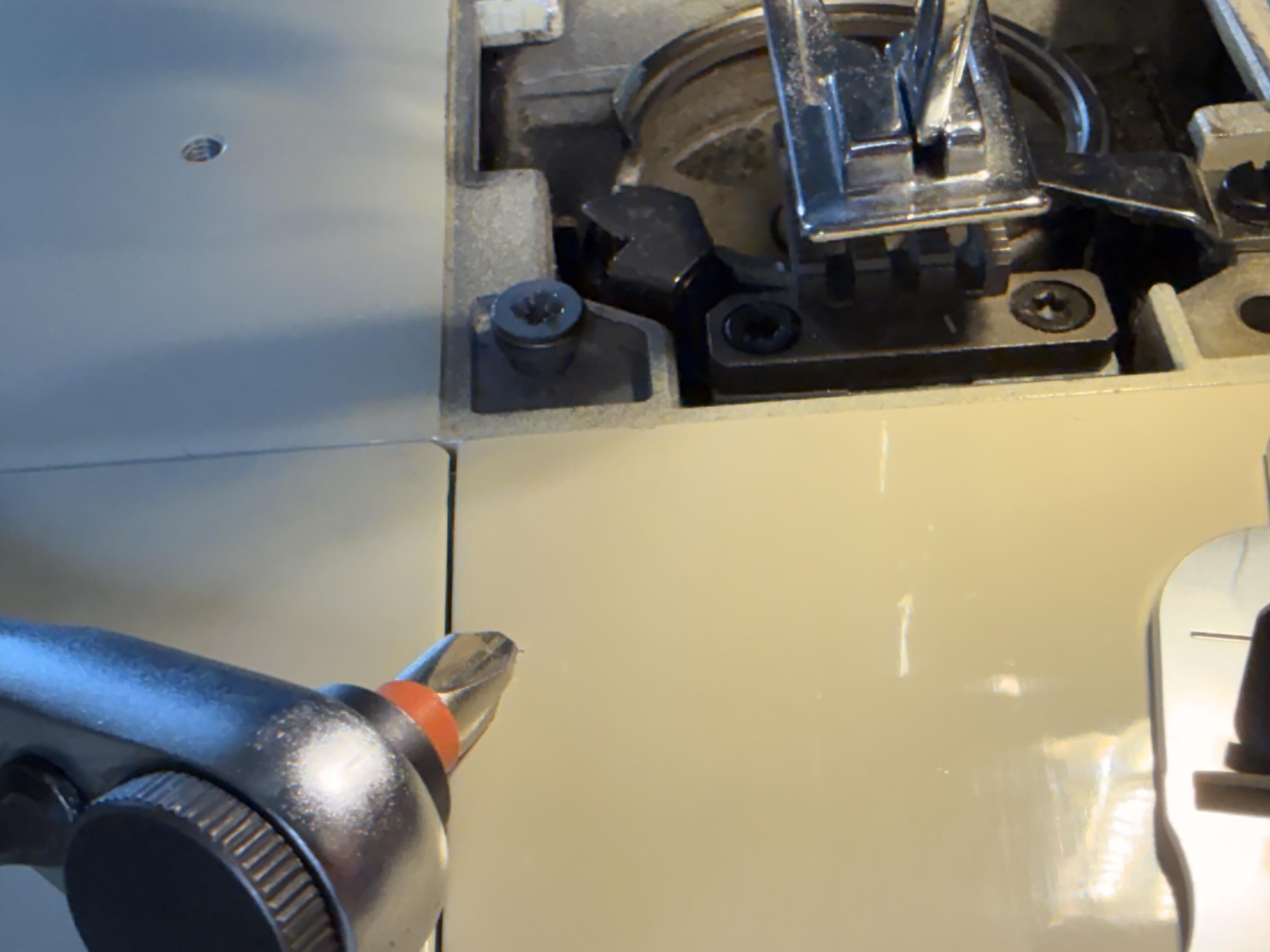 A Sears Kenmore 1980 sewing machine, bob and fruit plate with the throat plate removed and a screw visibly stripped