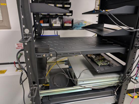 Side view showing a Xilinx AC701 devkit on the shelf below the hub