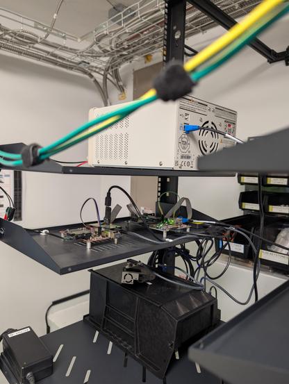 Two dev boards on a shelf with jtag dongles hanging off