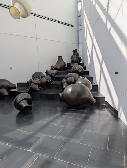 Stair shaped display in a corner with various spherical blobs that have smaller holes with a vaguely organic appearance