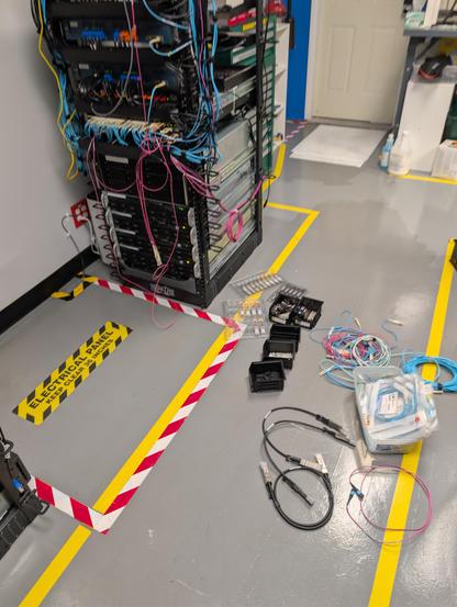 Server rack with half routed spaghetti everywhere and fiber cables on the floor next to it