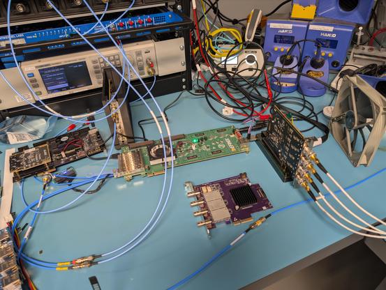 Three PCIe thunderscopes of various hardware revisions on a lab bench with various other devkits lying around