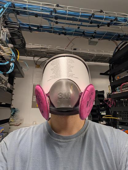Selfie of me in the lab wearing a 3M 6900 full face respirator with a brand new face shield still covered by the "remove this protective covering before use" sticker