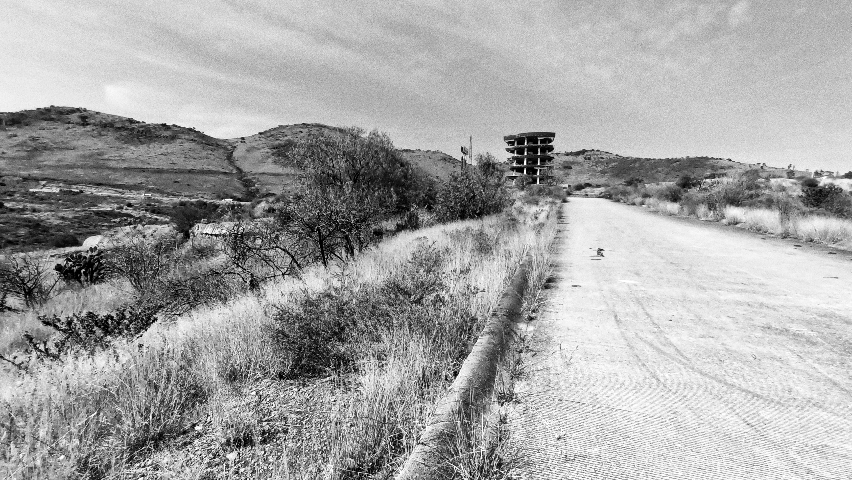 a photo of an abandoned tower among hills which was built supposedly to bring economic progress by a corrupted local govt. where some few years after its inauguration was abandoned