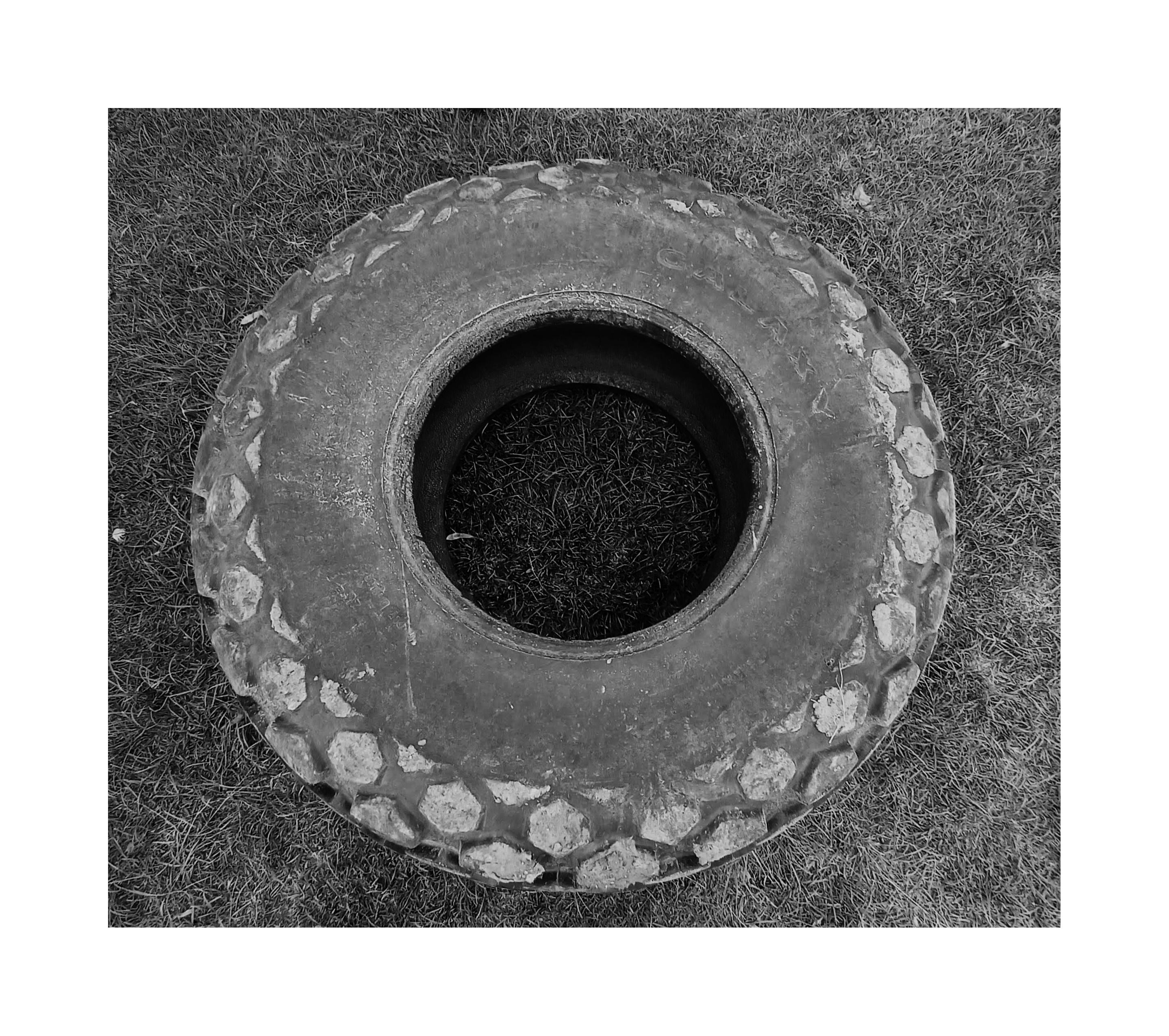 a photo of an abandoned truck wheel which was used as a seat on a park.