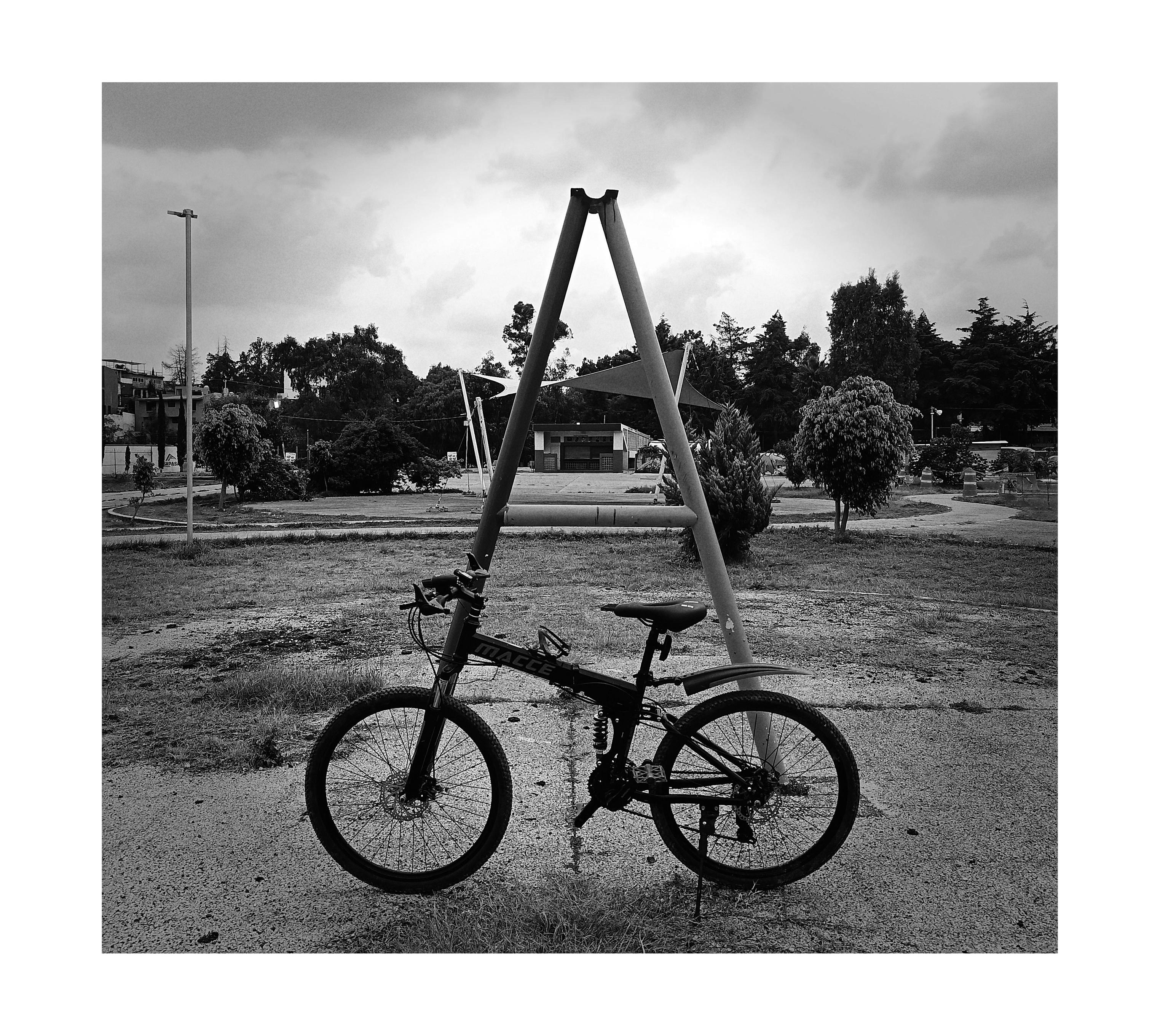 a photo of my bike in front of tubes that form a letter "A" of anarchism on the street