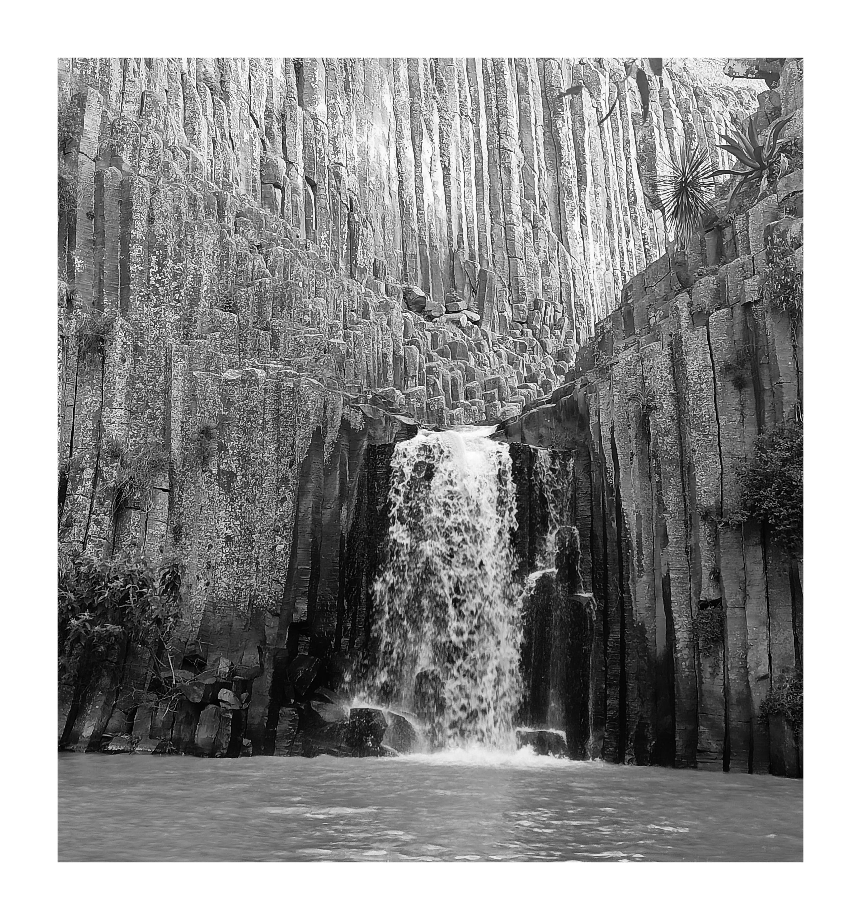 a B&W photo of the smallest waterfall from "prismas basalticos" in Hidalgo Mexico, a place where there are nature rock formations.