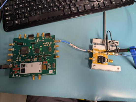 FPGA board outputting a pulse signal going through a SMA cable into a test fixture with a 10x r-c probe on it