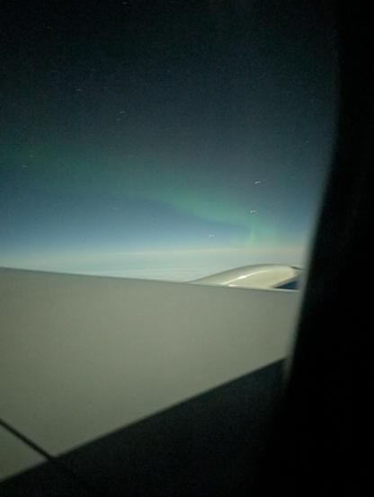 Green aurora seen above the wing of an airliner