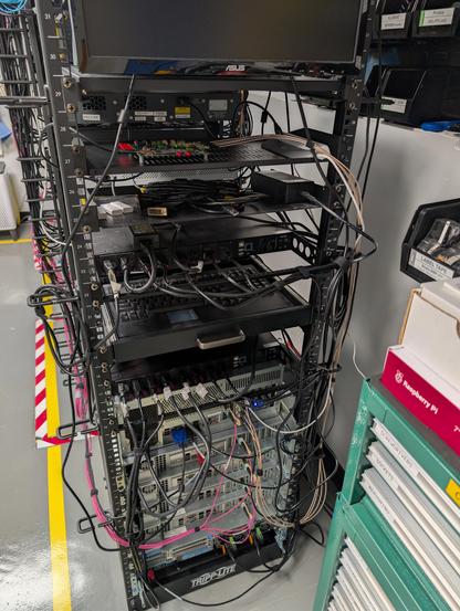 Back of a 19" rack showing fiber and coaxial cables running to various equipment