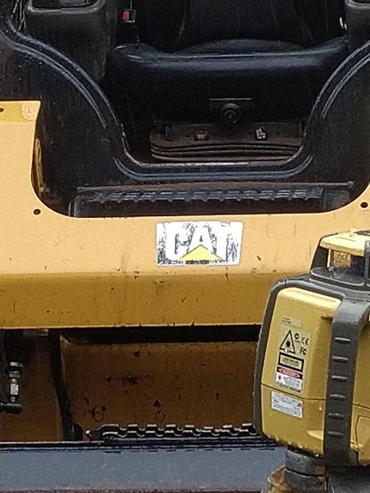Front bumper of a CAT mini excavator in front of a total station