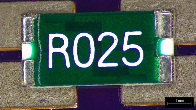 Green 4-terminal resistor labeled "R025" with silver terminals sitting on solder paste.

A zigzagging strip of resistive material can be seen through the green overmolding.