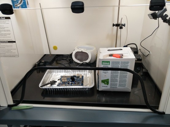 Trigger crossbar board in an aluminum tray in the fume hood next to a jug of cleaning fluid