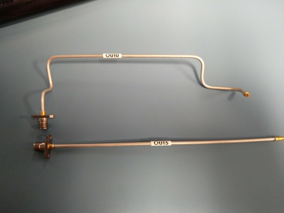 Two semi rigid cables, one labeled "OUT0" bent into shape and then other labeled "OUT5" and unbent.