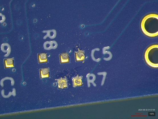Microscope view of two 0402 component footprints with sorry-looking solder paste deposits on them