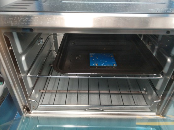 Blue PCB inside an oven with an open door