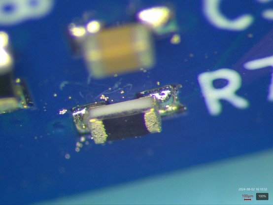 0402 thick film resistor exhibiting the same failure mode, with loose solder spheres floating around